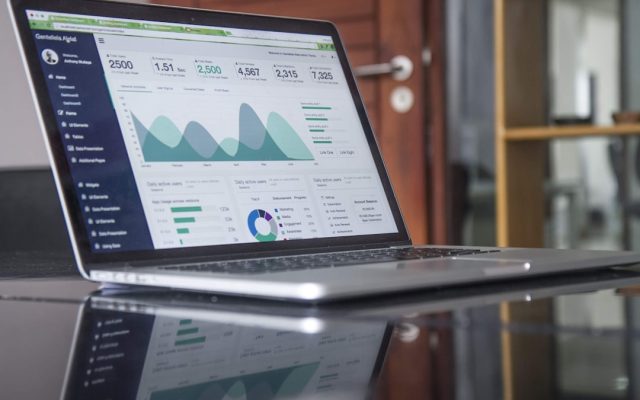 A laptop showing website analytics beside a notebook and phone.